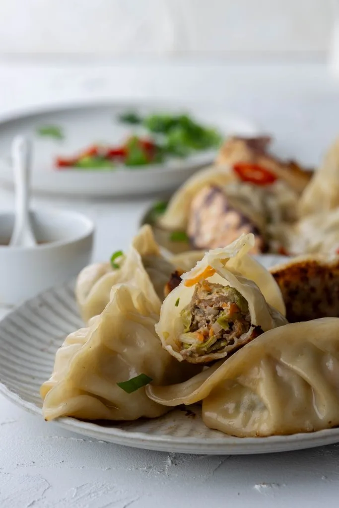 stack of pan fried dumplings with bite mark showing filling