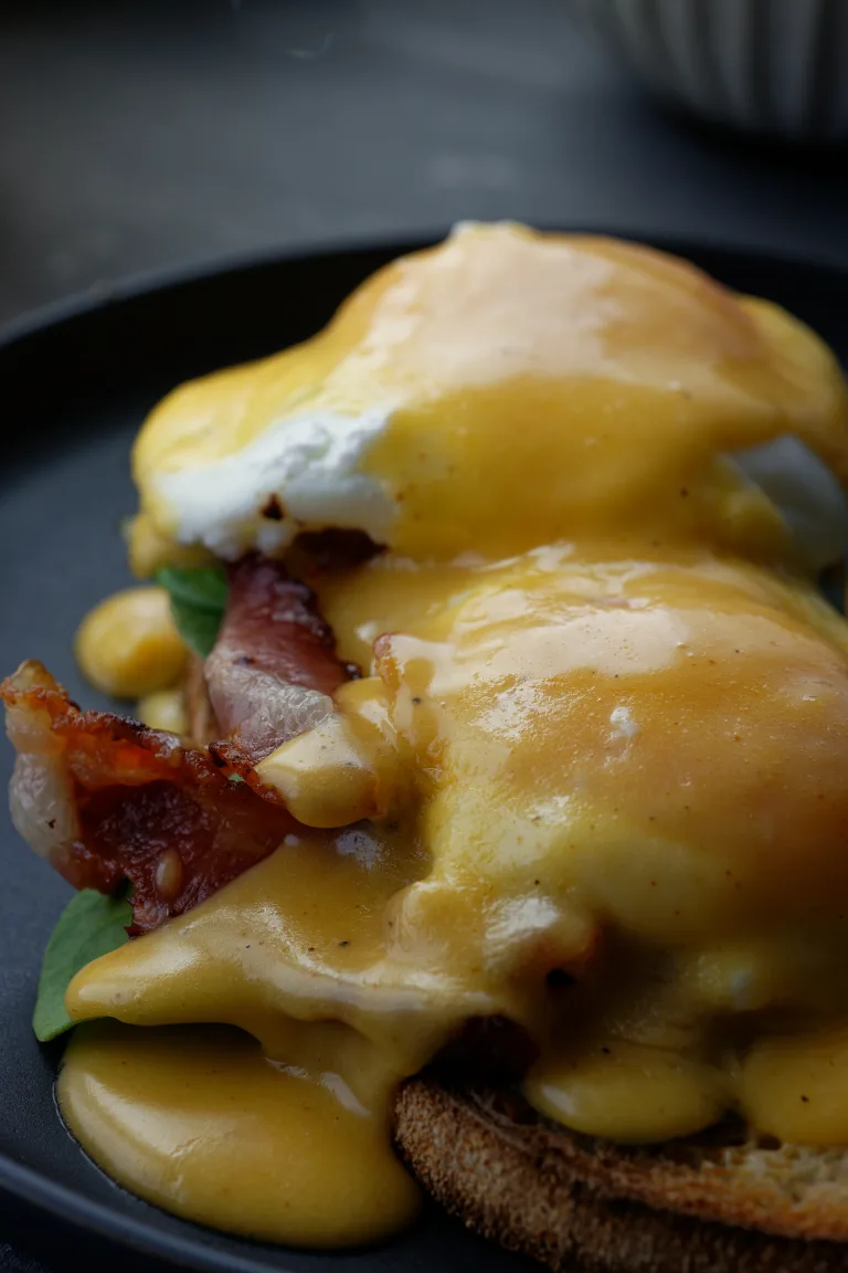 Eggs benedict with hollandaise on grey plate