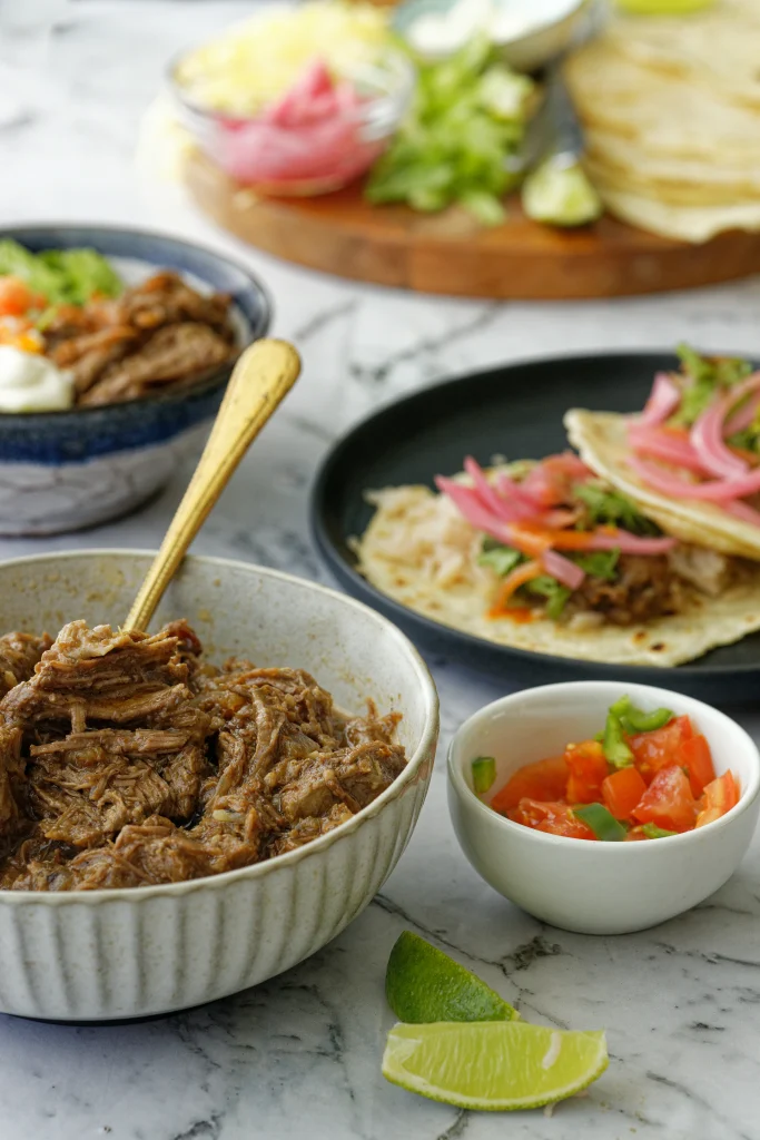 Dinner table with bowls of beef, tortillas and vegetables