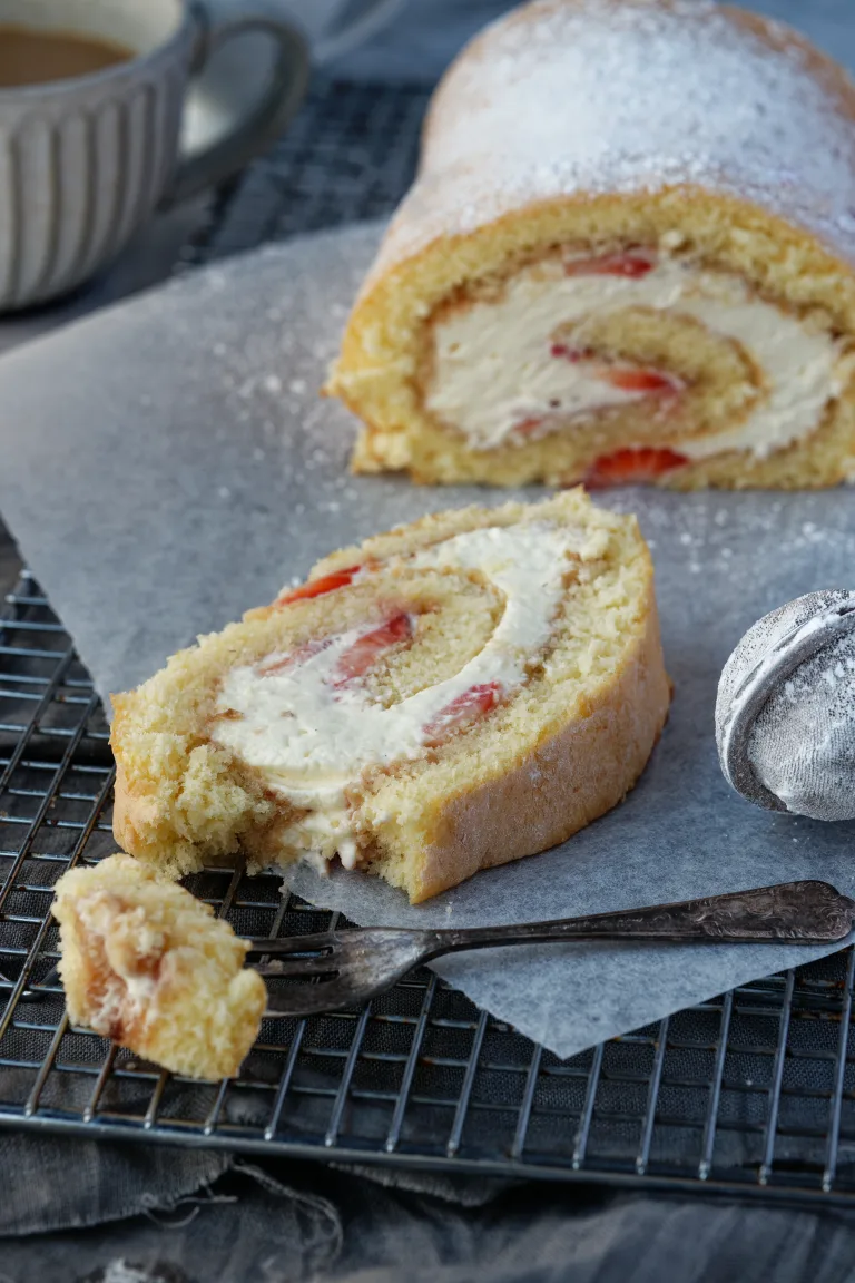 Fork in foreground with berry swiss rolle cake behind