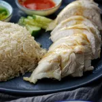 Hainanese chicken breast sliced on grey plate with cucumber