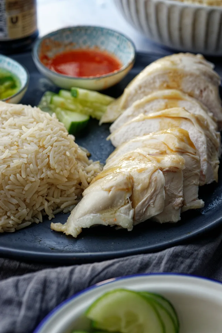 Hainanese chicken breast sliced on grey plate with cucumber