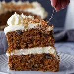 Fork scooping carrot cake with cream cheese frosting