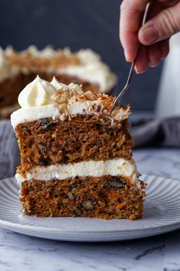 Fork scooping carrot cake with cream cheese frosting
