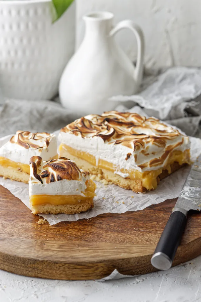 Lemon Meringue slab cut into squares on wooden plate