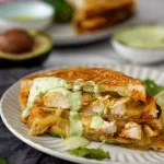 Cross section of chipotle chicken toasted sandwich with ingredients used in background.