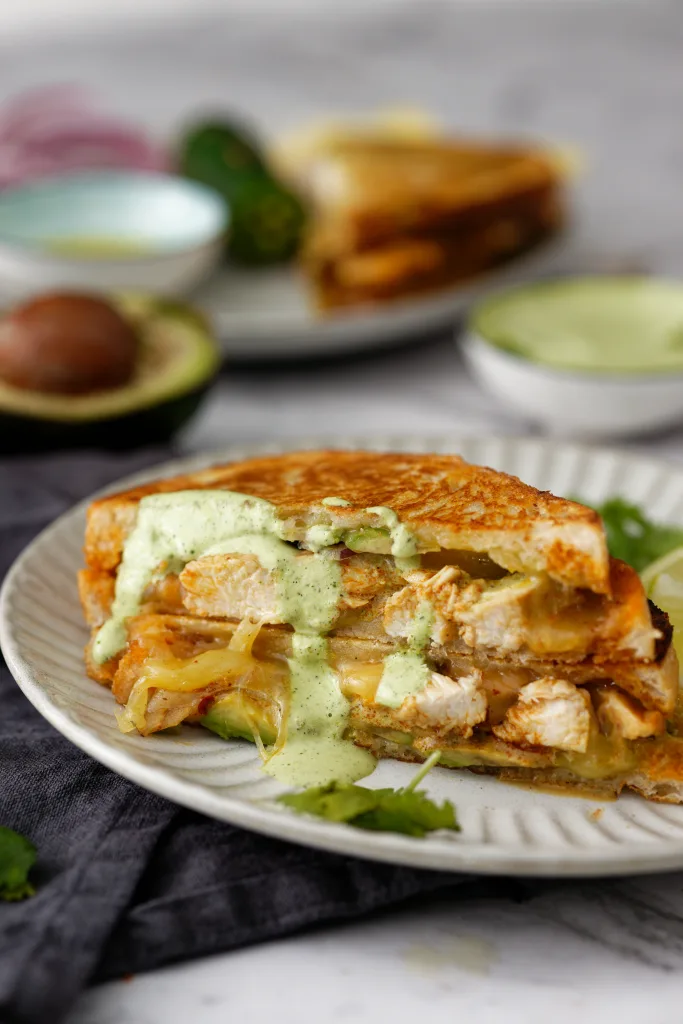 Cross section of chipotle chicken toasted sandwich with ingredients used in background.