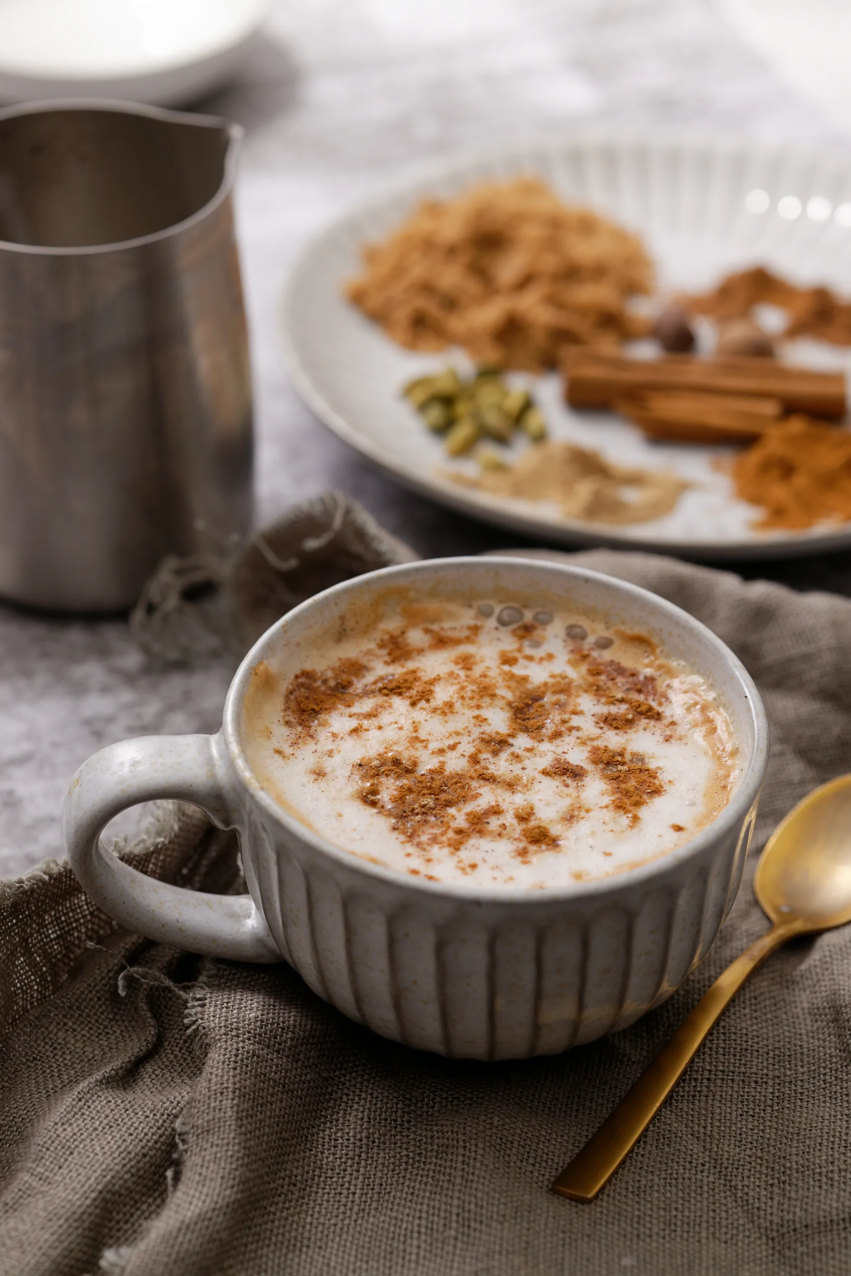 Chai spiced coffee in mug with spices used to make it in background