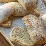 ciabatta Bread on baking tray with one loaf cut in half