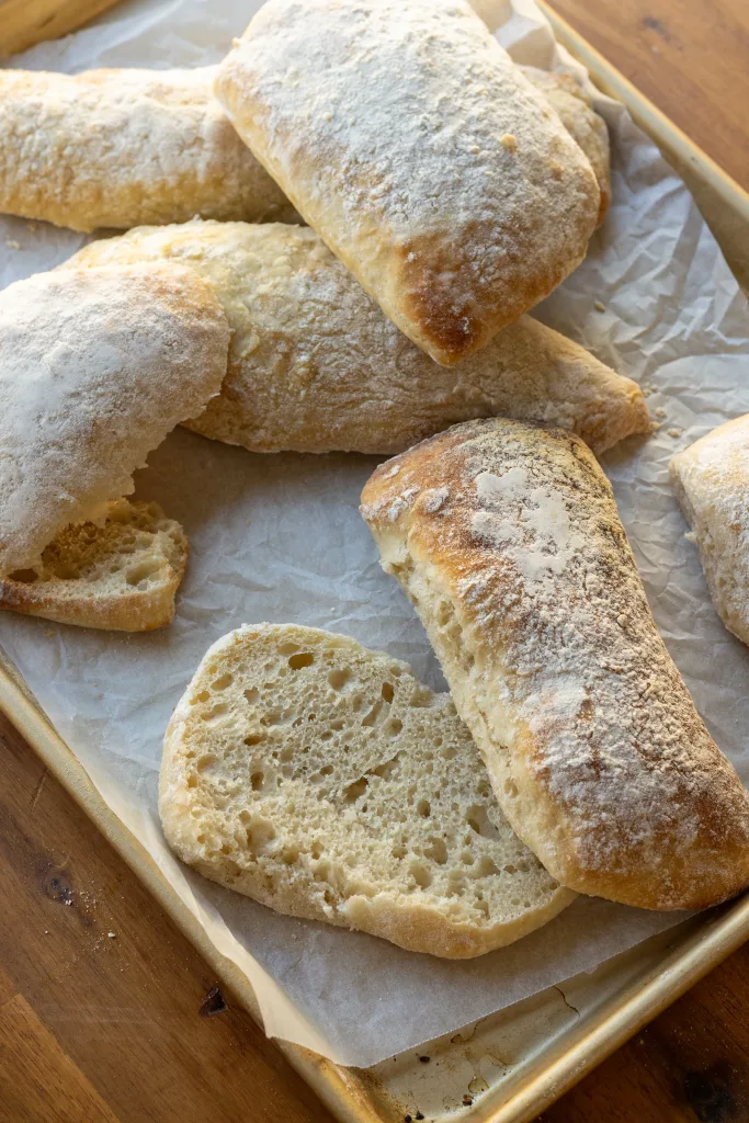 No knead Ciabatta Bread on baking tray with one loaf cut in half