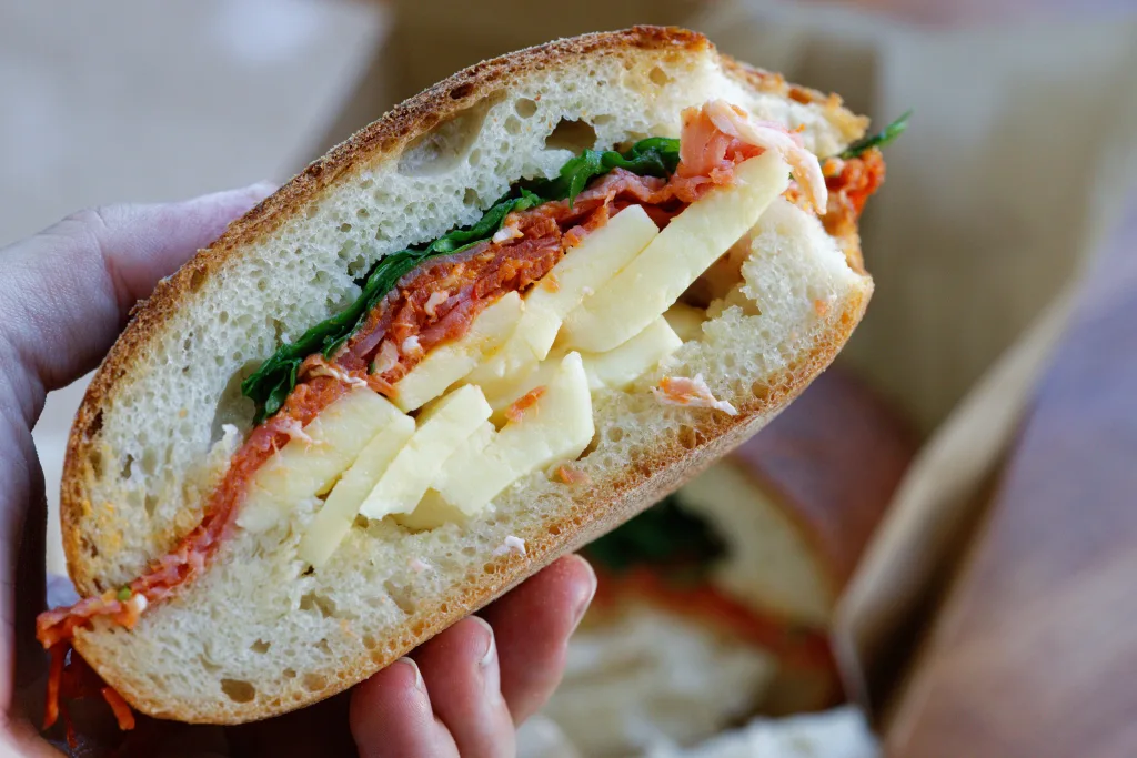 cross section of ciabatta sandwich filled with salami, cheese and rocket/arugula