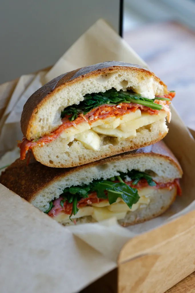 Panni Sandwich cut in half sitting in takeaway container