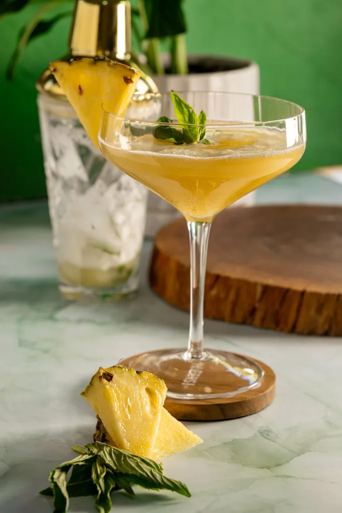 Coupe martini glass with garnishes and cocktail shakes in background