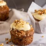 Spiced pineapple banana cupcake topped with frosting and topped with chopped walnuts