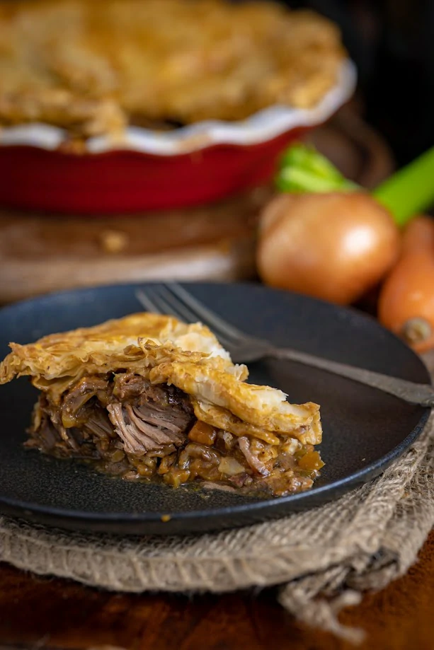 Slice of beef pie topped with puff pastry